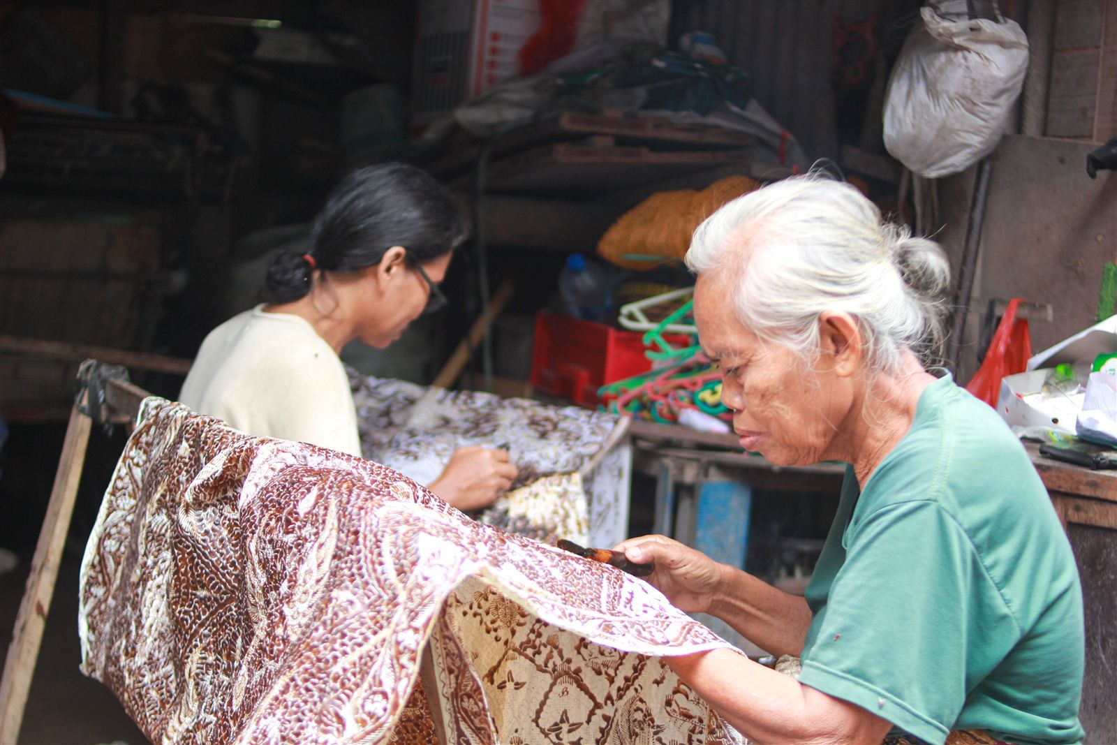 Perajin batik menorehkan lilin malam pada kain